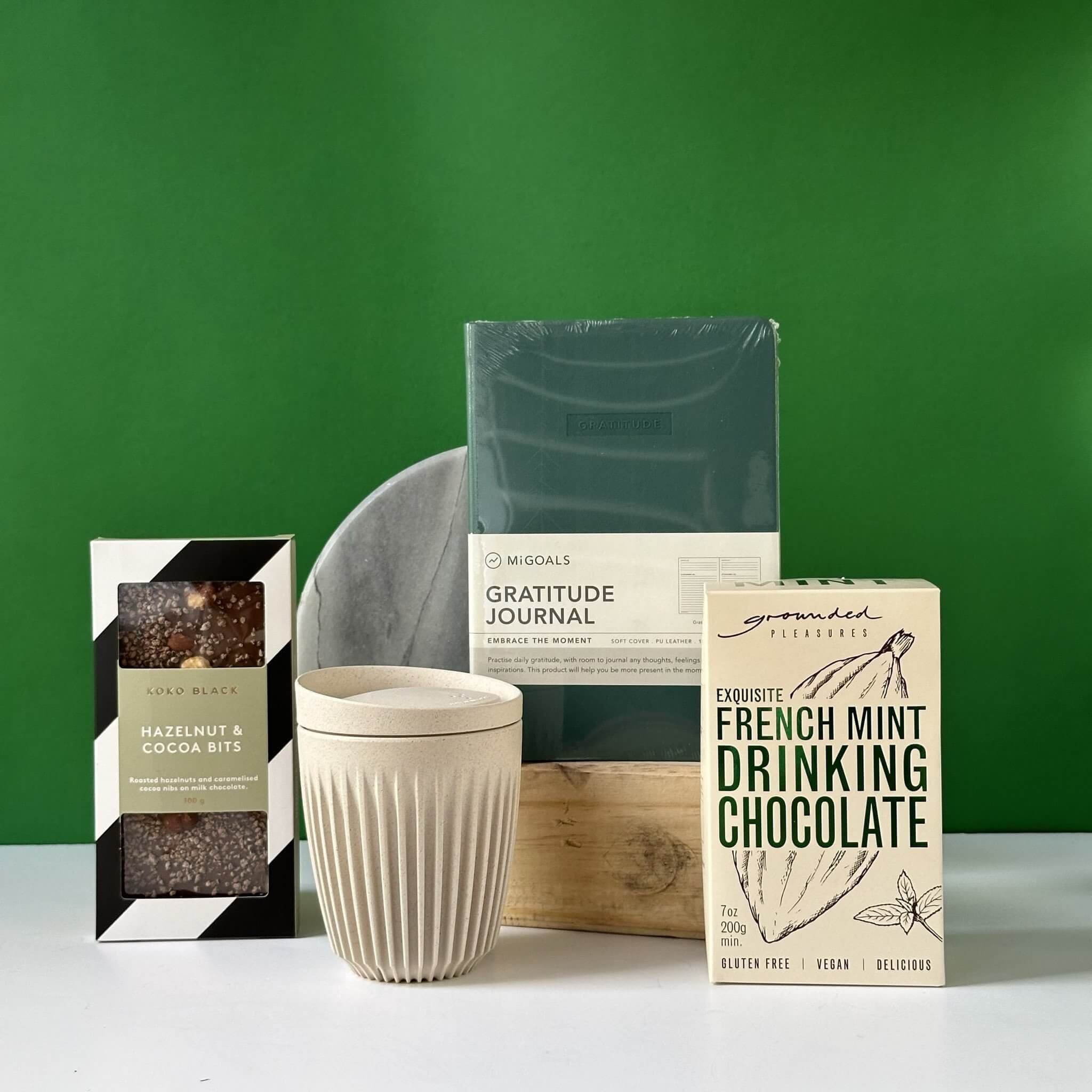 The Grateful for You gift bundle featuring a Migoals Gratitude Journal, Huskee reusable coffee cup, and Grounded Pleasures French Mint Drinking Chocolate, elegantly packaged in Thankly’s signature black box.