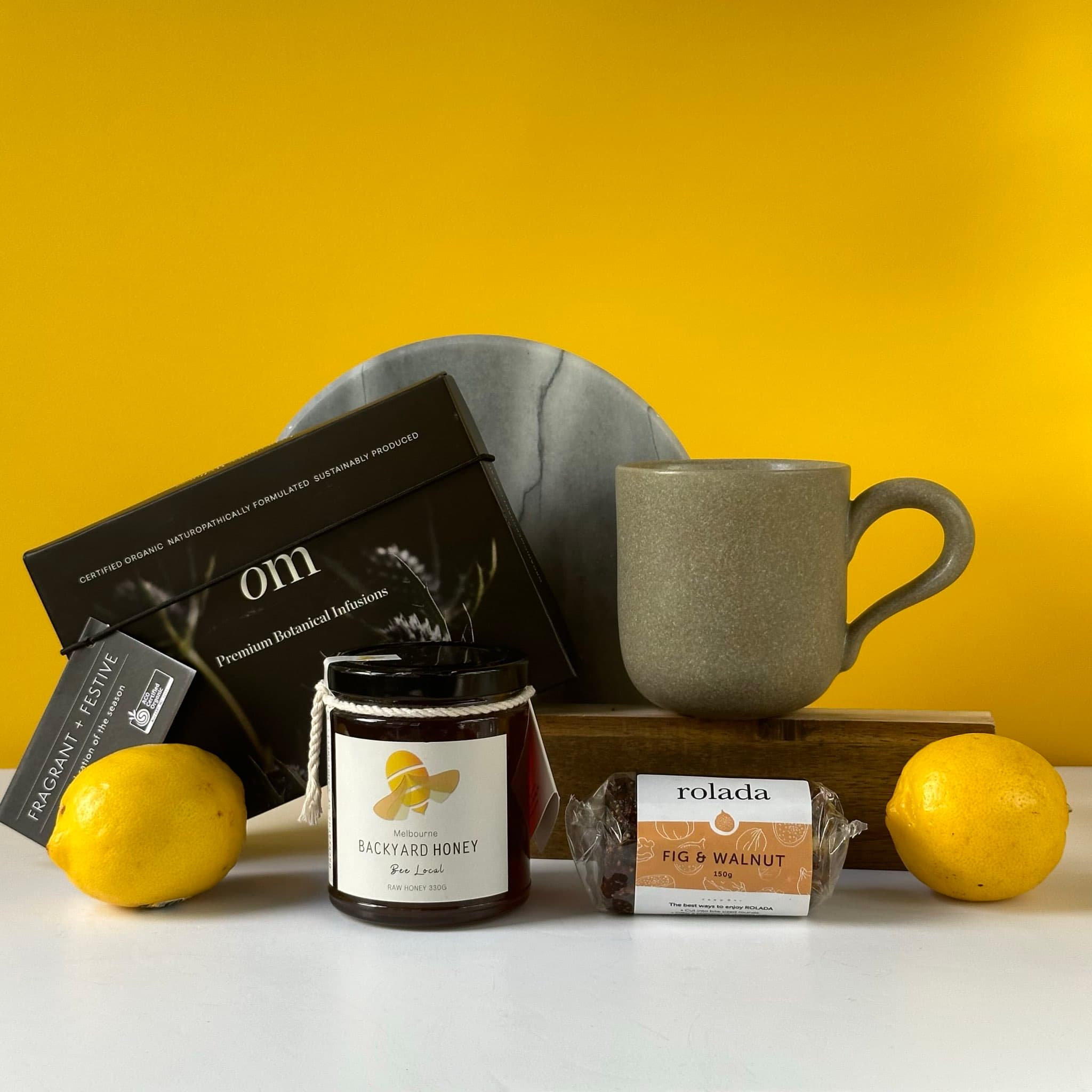 A cozy gift bundle featuring a Robert Gordon mug, raw honey, fig & walnut Rolada, and a botanical tea gift set with an infuser, all beautifully packaged in a premium Thankly box.